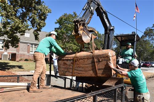 Time capsule being hoisted from ground and loaded on truck 